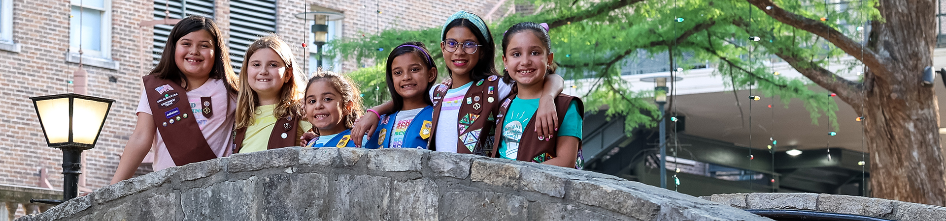  group of young girl scouts standing on a riverwalk bridge 