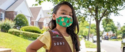 Everything you need for back to troop Confident standing girl in a green mask that has Girl Scout cookies on it