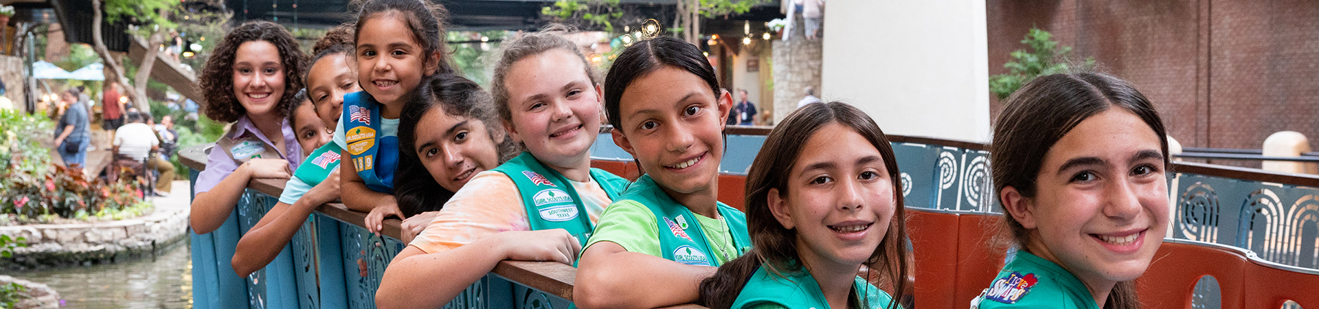  Group of girl scouts in vests sitting on a riverwalk boat and smiling  