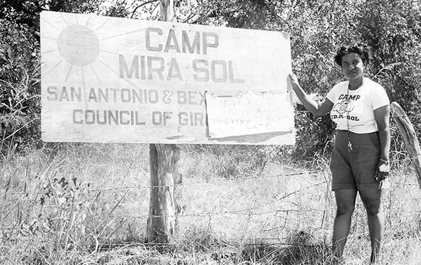 1950s image of camp counselor standing next to Camp Mira Sol sign