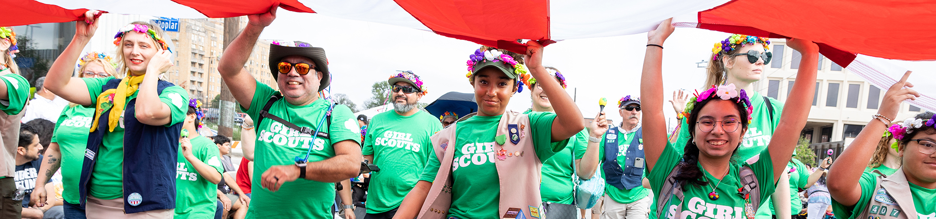  volunteers and girls carry the American flag in the Battle of Flowers Parade in April 2023 