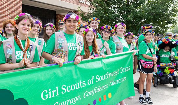 Girl scouts in vests holding battle of flowers parade banner