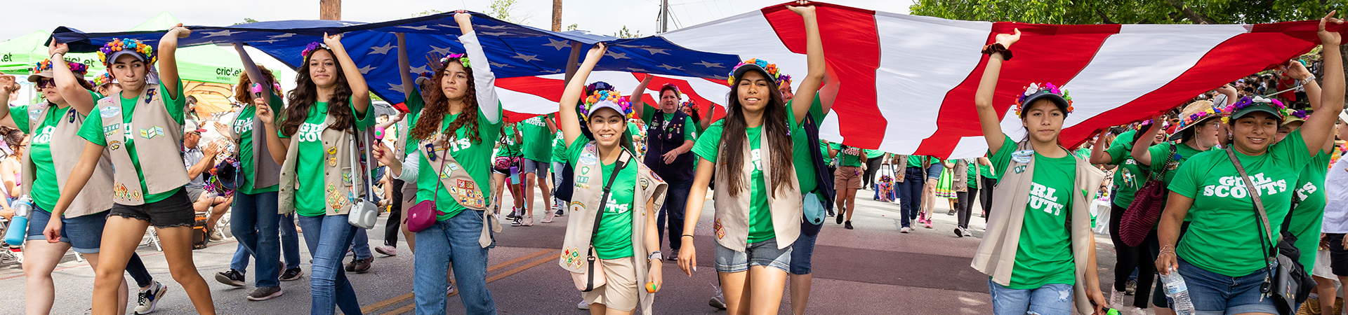 Several Girl Scouts holding up the American flag above their heads at the Battle of Flowers parade 