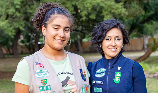 adult volunteer in vest next to a Girl Scout in uniform