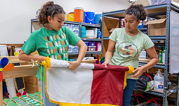 two girl scouts rolling up flag