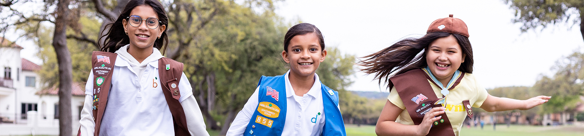  three girl scouts running outside and smiling 