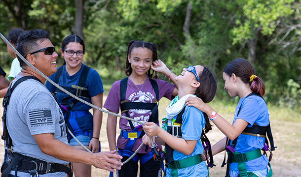 girls laughing while getting ready to do the ropes course