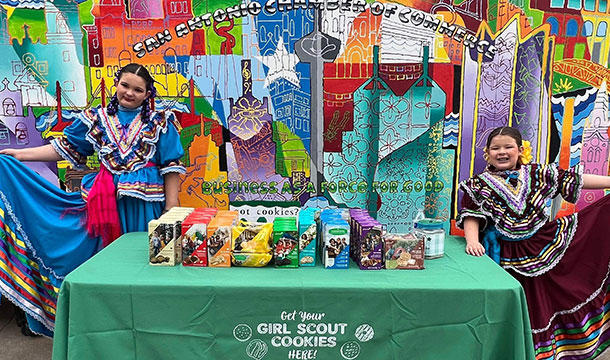 two girl scouts in fiesta dressed at a colorful cookie booth 