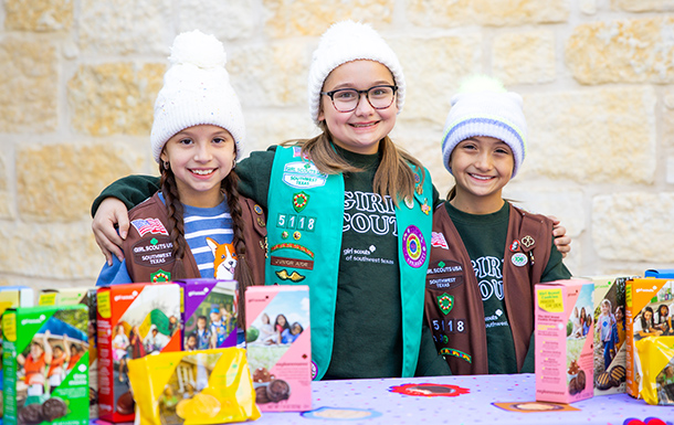 girl scouts pose at a cookie booth