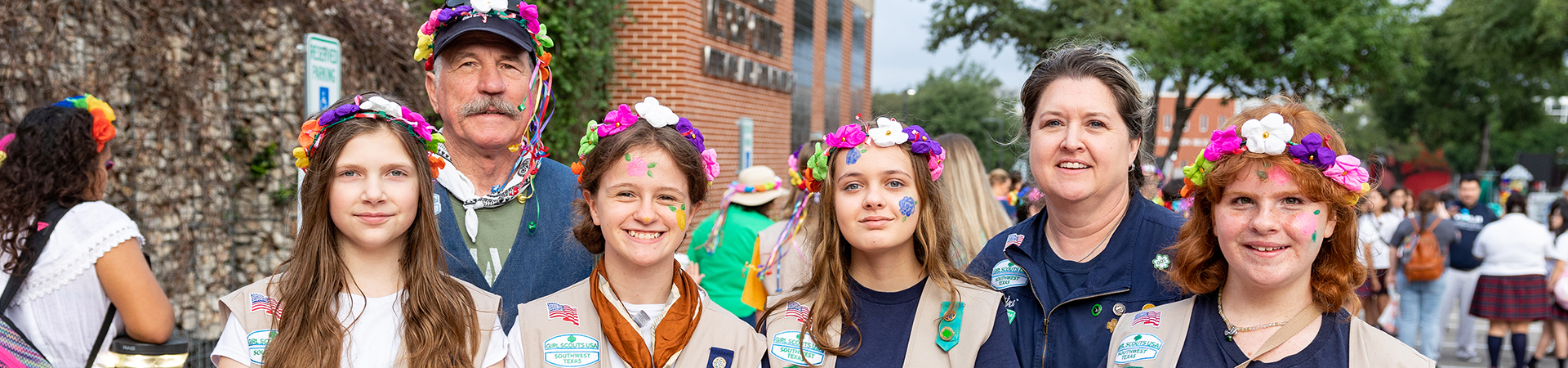  Girl Scout volunteers with a group of Girl Scouts smiling outdoors 