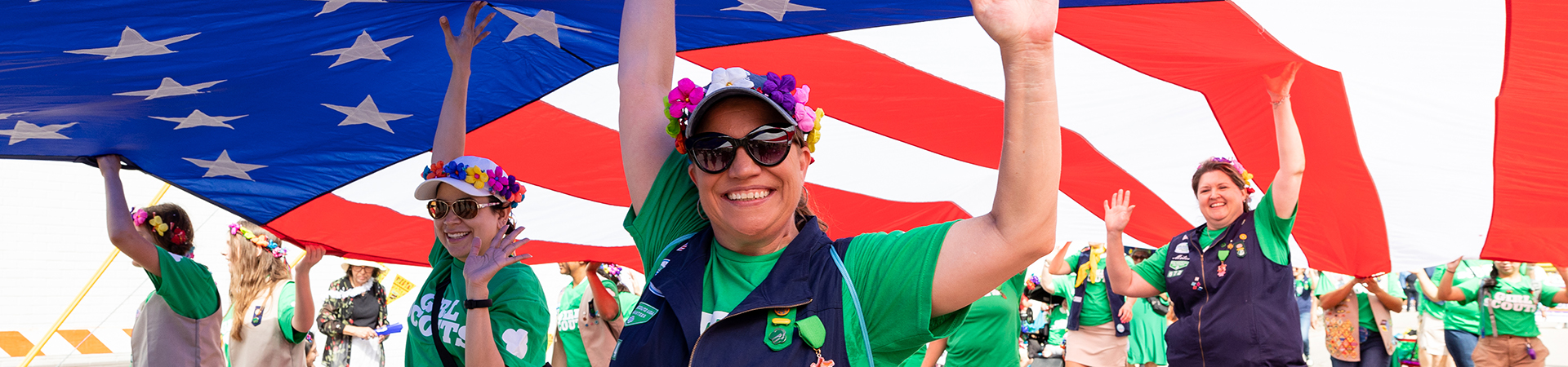  adult volunteer in vest outside holding up american flag in parade 