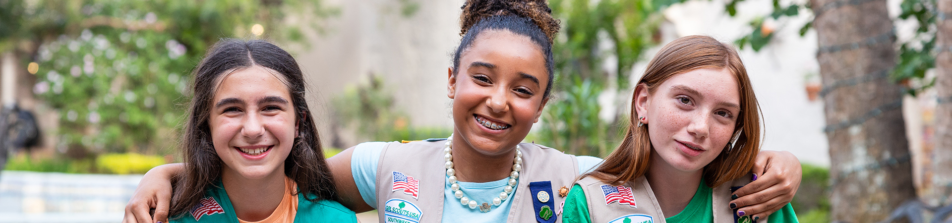  three girl scouts with arms around shoulders smiling 