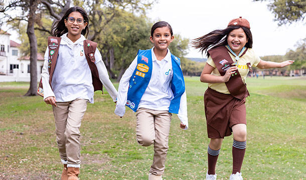 girl scouts running in a gold course field